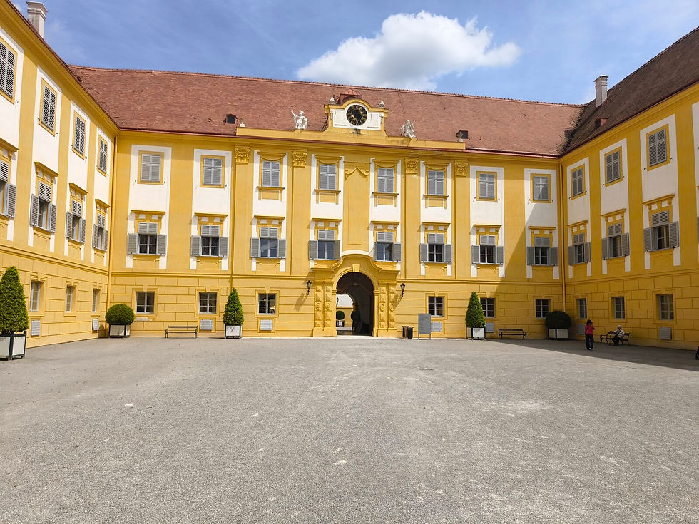 Schloss Hof Fassade vom Ehrenhof, gelbe Hauptfront mit barocker Uhr und Skulpturen