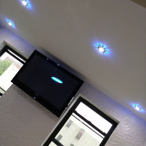 Wall-mounted TV below tile-finished ceiling with blue halo LED downlights—secure stud mount, cables hidden, Manhattan apartment
