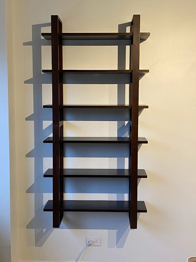 Wall-mounted wooden bookshelf securely installed and leveled on interior wall.