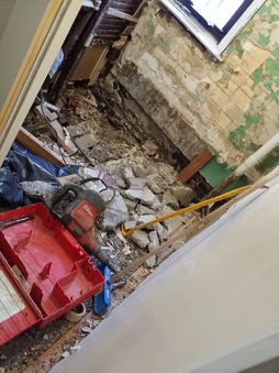 Bathroom under demolition with rubble, exposed masonry and studs, and floor opened for drain—preparation for custom walk-in shower in Manhattan, NY.