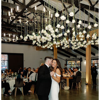 bride and groom dance beneath floral installation of white roses