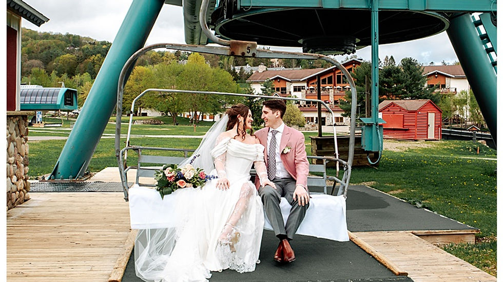 bride in wedding dress from Bridal Chateau and groom in suit from AJ Custom Suits on ski lift at Holiday Valley