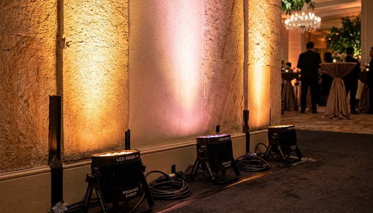 Close-up of LED uplights washing a textured wall in warm amber and soft pink tones.