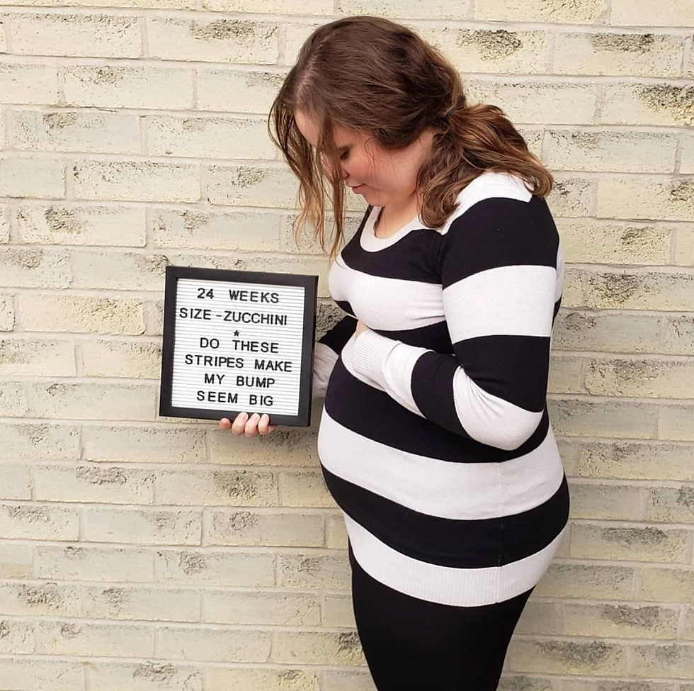 pregnant woman looking down holding a sign