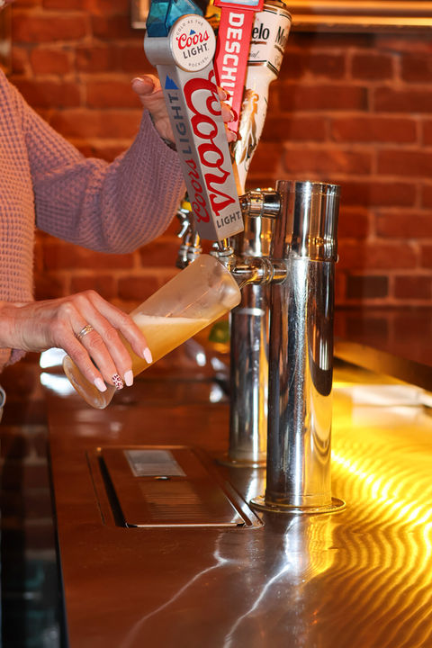 Employee pouring coors into tall beer pitcher