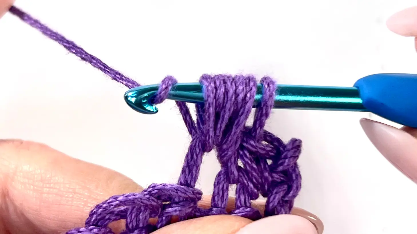 Crochet hook holding multiple loops from yarn-overs in the Bean Stitch process, preparing to yarn over and pull through.