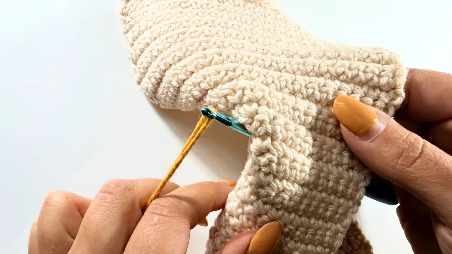 Inserting the crochet hook through the sleeve to begin the surface crochet design.