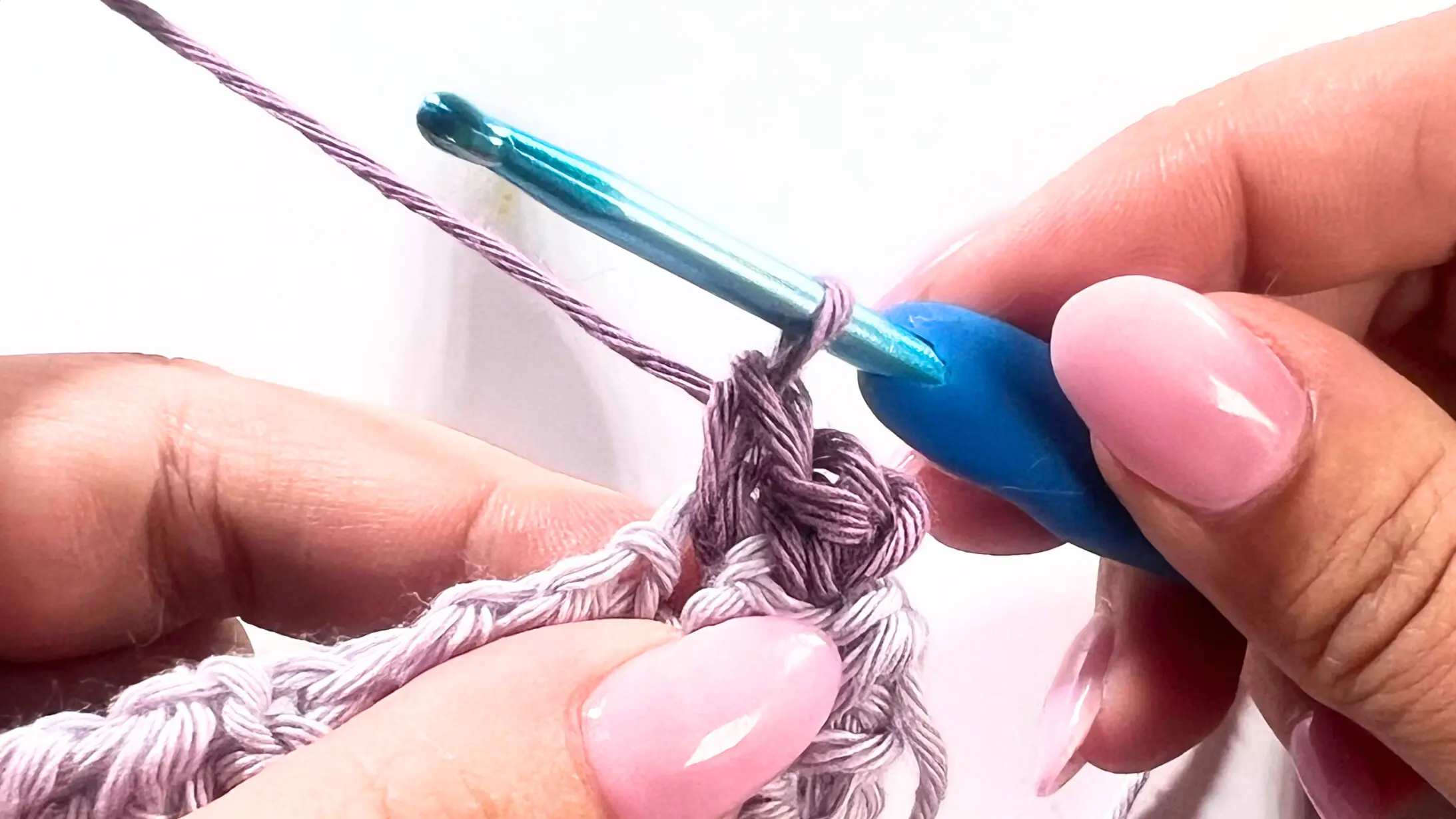 Close-up of crochet work showing a single crochet made in the next stitch, followed by a chain of three to begin the picot.