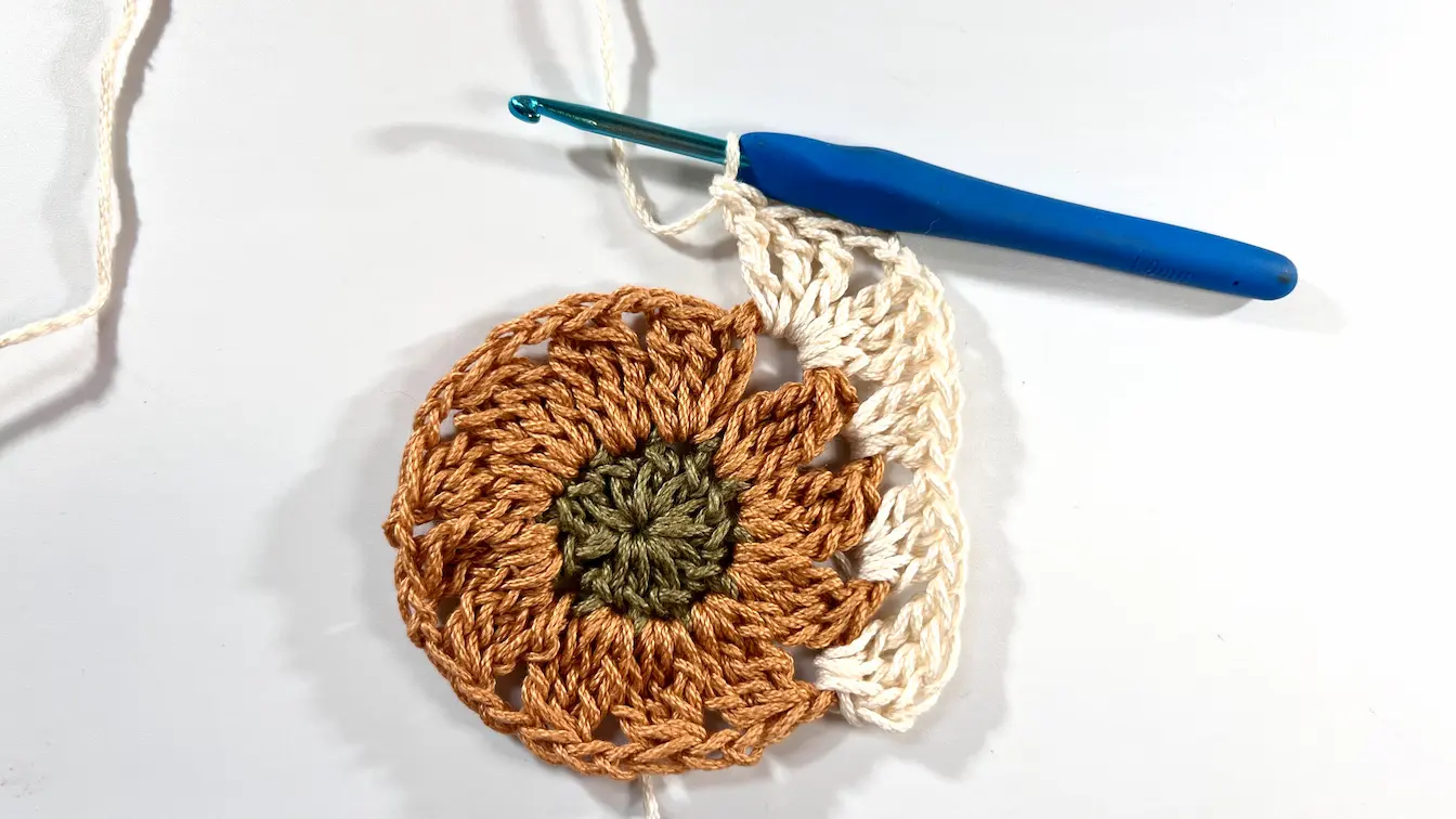 Working the first square corner using treble crochets and chain spaces on the Daisy motif.