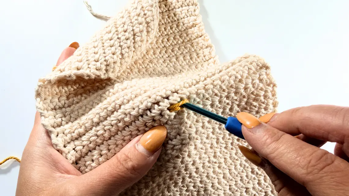 Pulling the yarn through the sleeve to begin the first surface slip stitch.
