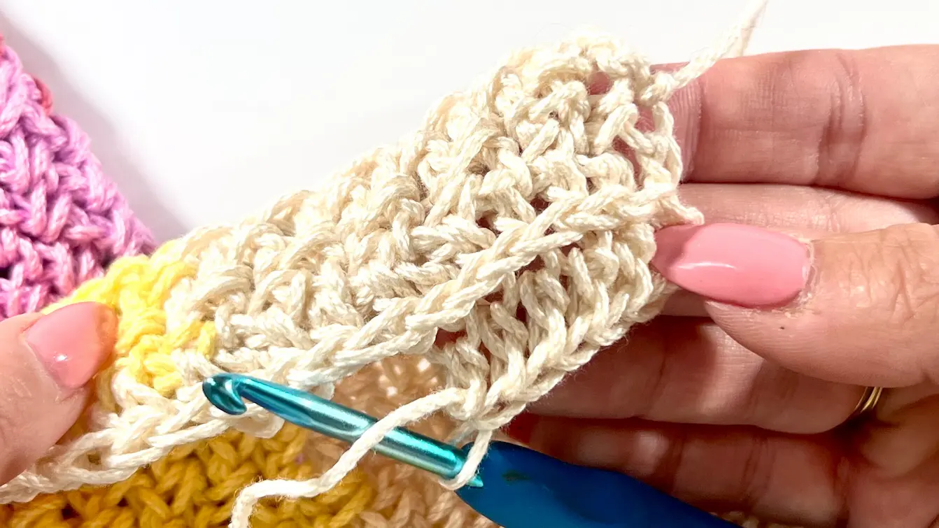 A crocheted fabric worked in Half Double Crochet into the front loop, with top V-shaped loops pushed to the side to create a distinctive horizontal texture.