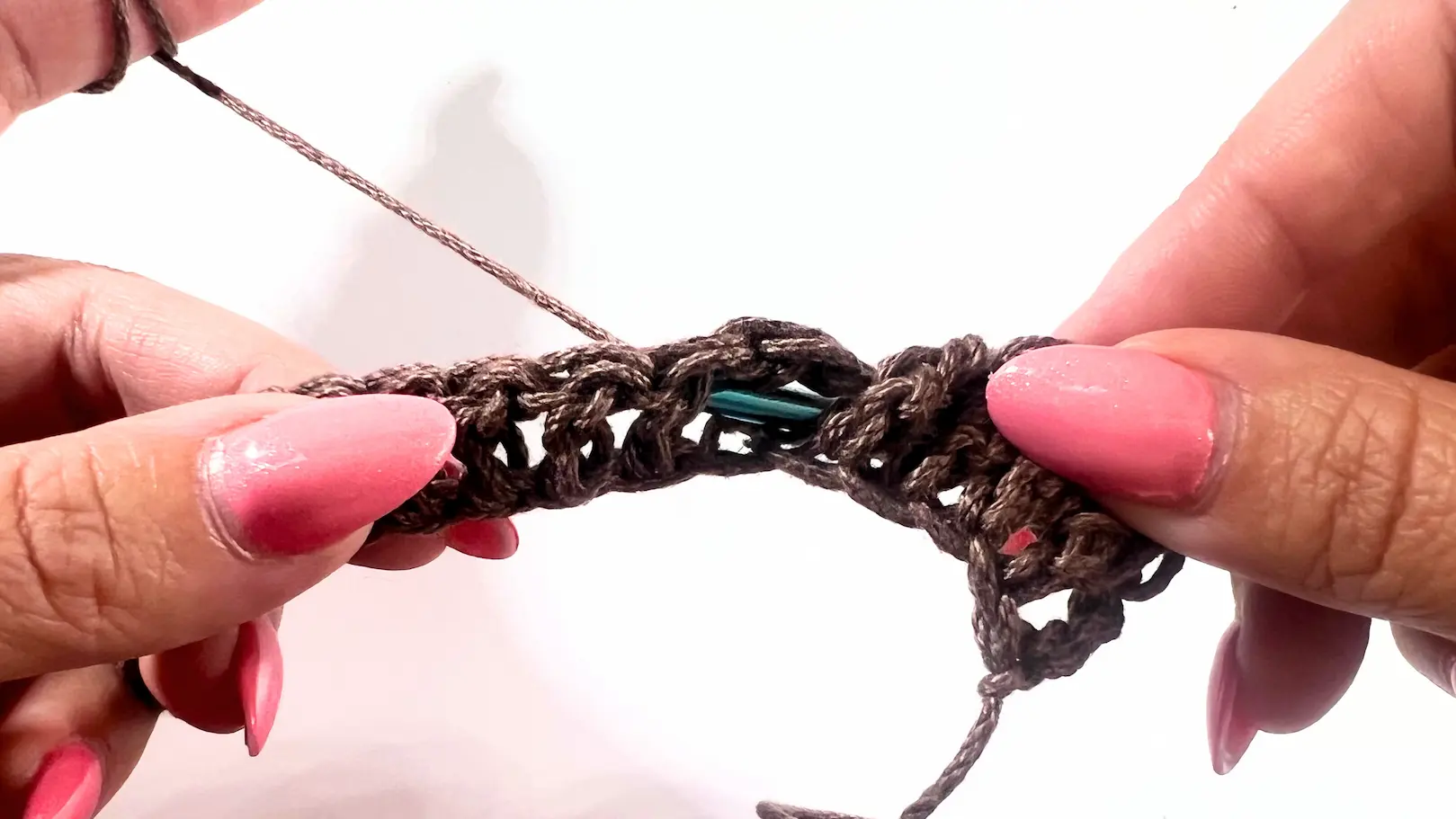 Hook shown inserted from the back around the post of the next stitch, demonstrating the setup for a Back Post Double Crochet (BPDC).
