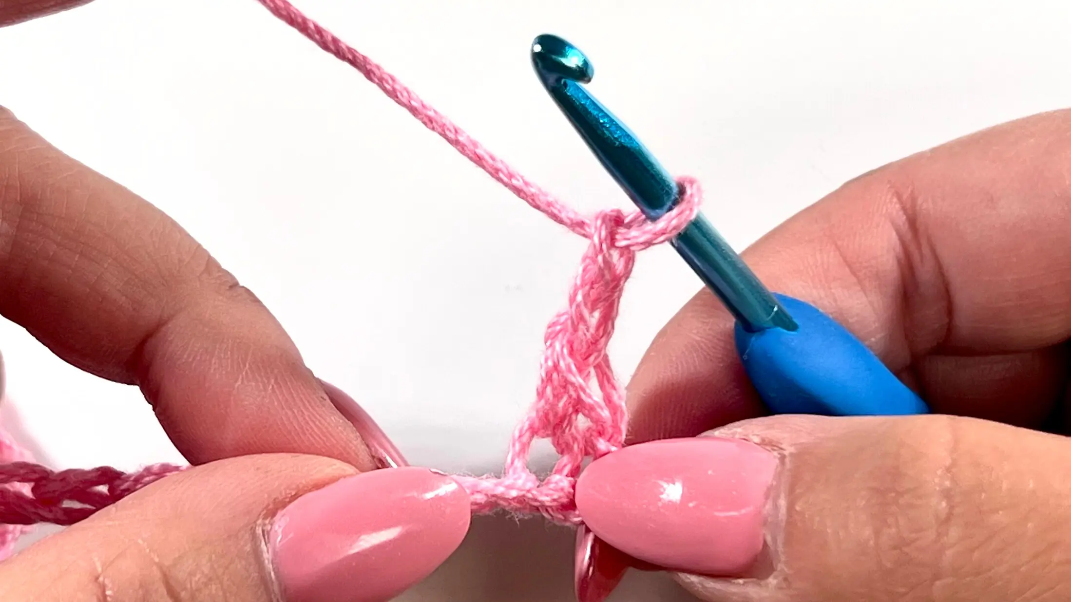 Chain 2 created after completing part of the Primrose Stitch cluster, held by blue crochet hook.