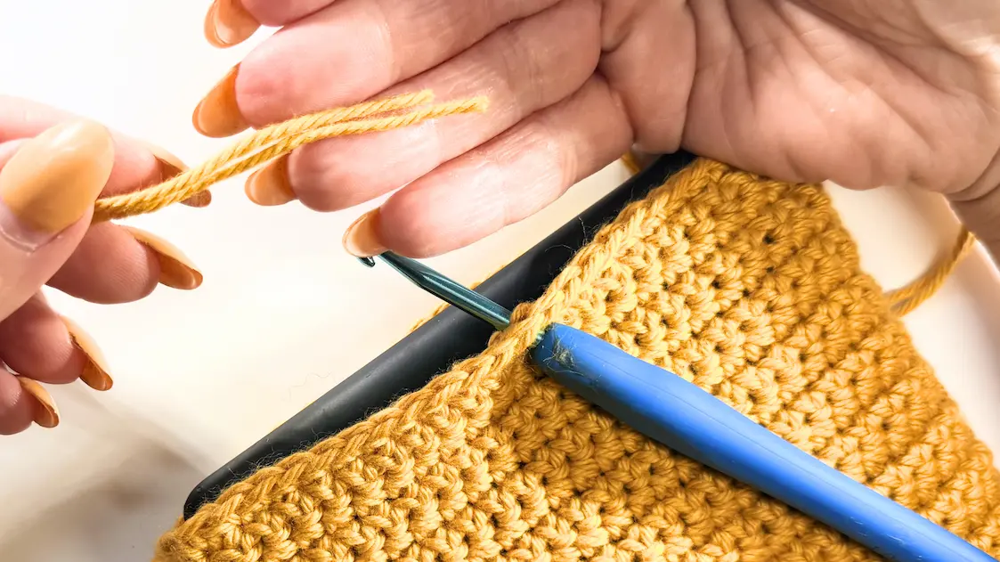 Attaching yarn at the center back of the sleeve to begin the button loop closure.