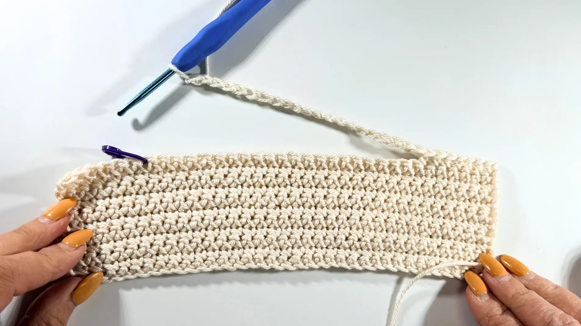 Long crochet rectangle with a chain section worked across the top and a stitch marker marking the placement.