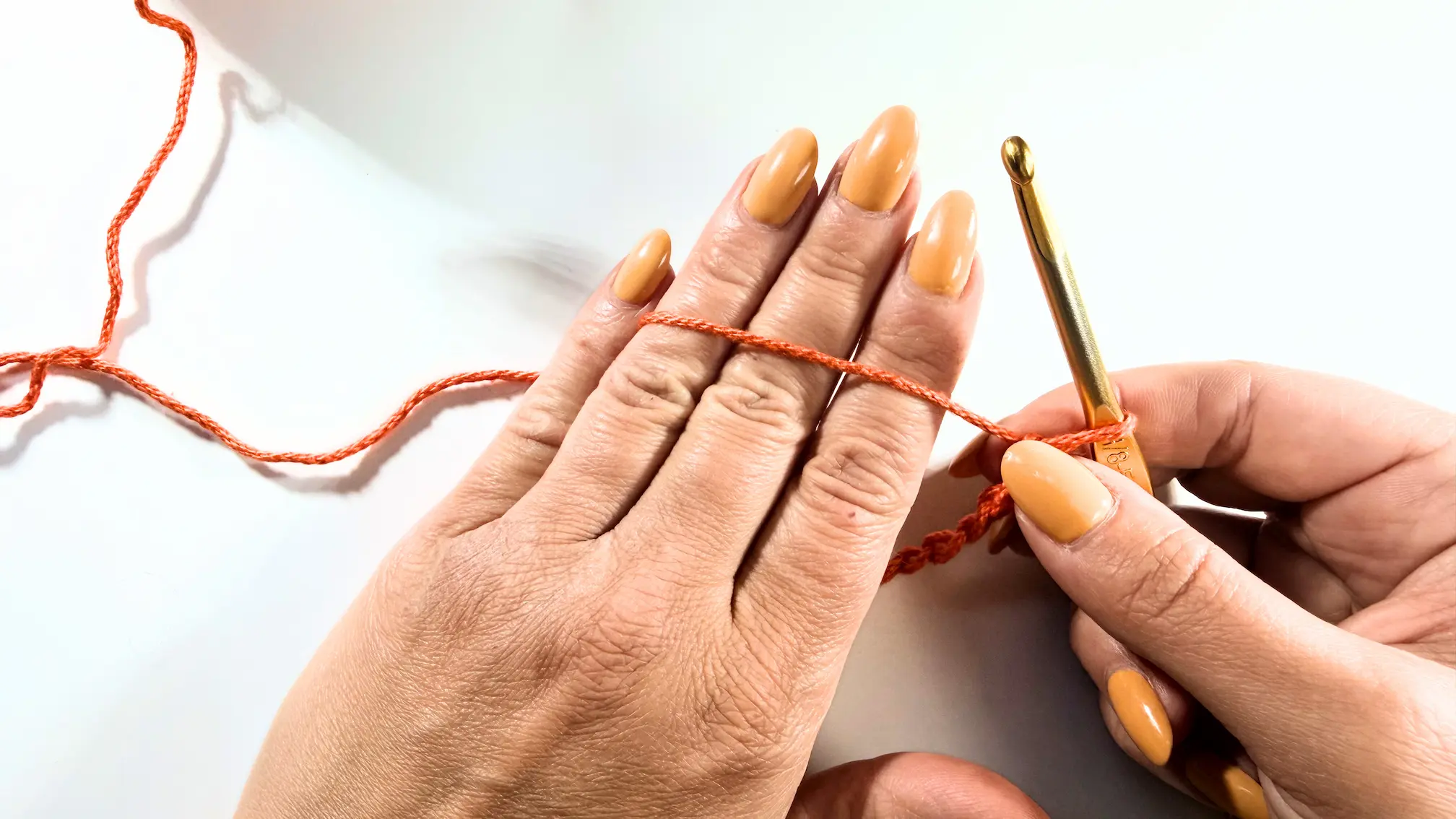 Close-up of yarn wrapped around fingers to demonstrate one method of holding crochet yarn for tension control.