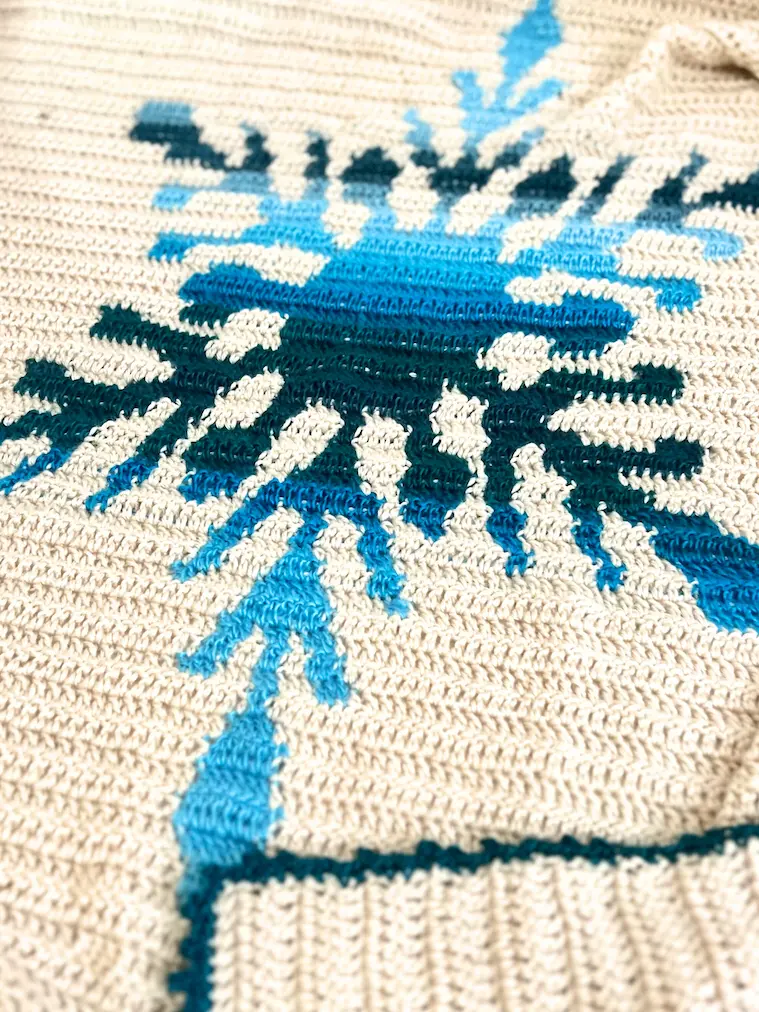 Detailed view of the lower point of the snowflake on the Northern Flakes crochet blanket with visible stitch texture.