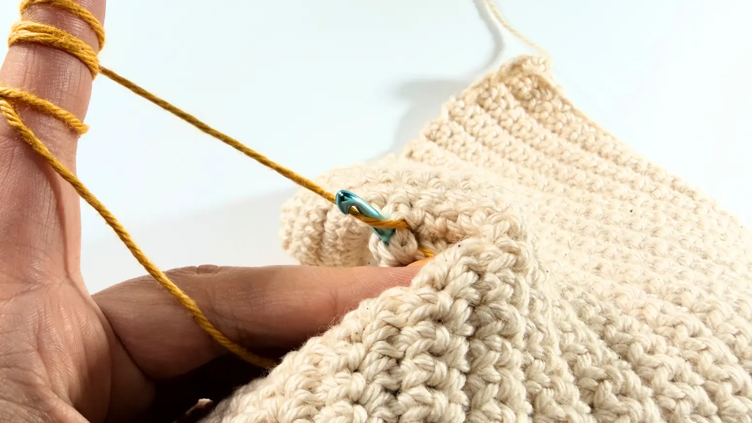 Working a surface slip stitch by pulling the loop through the fabric and the loop on the hook.