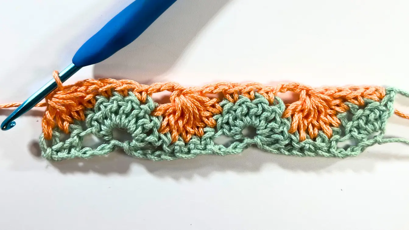 Completed two rows of the Catherine Wheel Stitch in green and orange yarn, showing the finished look of the first full colour repeat.