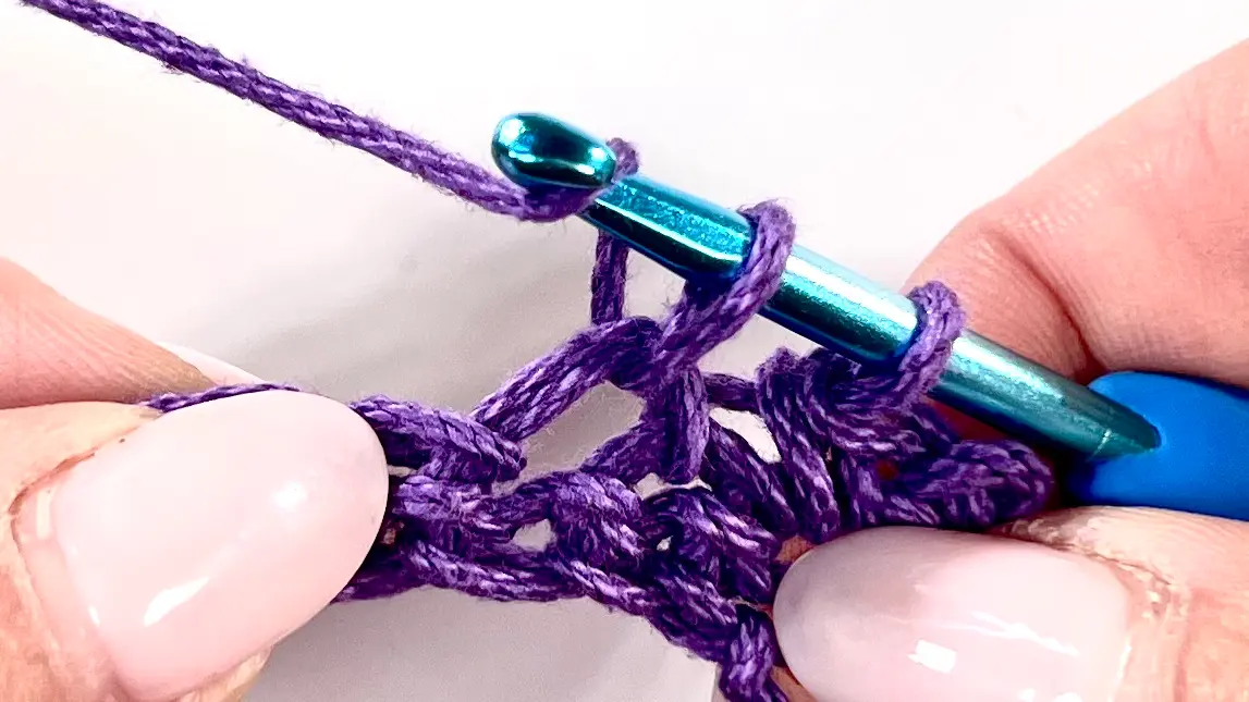 Yarn wrapped around the hook as the second loop is pulled through for the Bean Stitch, showing tension and stitch build-up clearly.