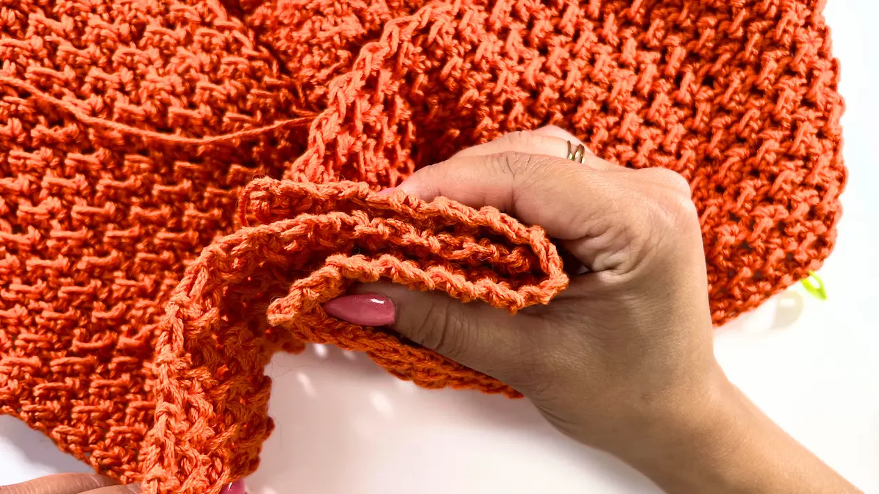 Close-up view of the folded crochet center section, showing the texture of the Even Moss Stitch in burnt orange yarn.