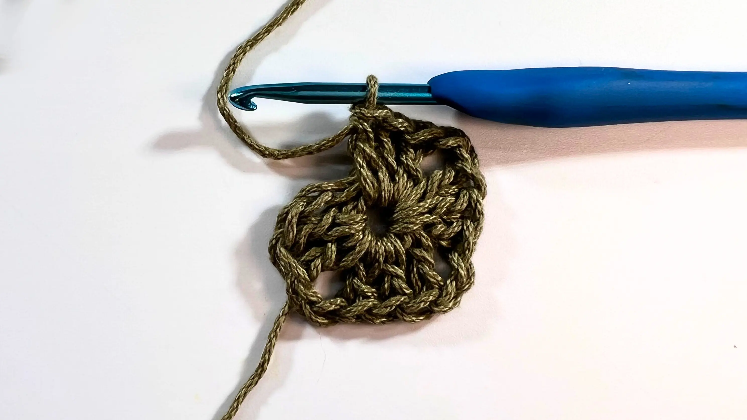 Granny square showing three completed corners with clusters forming along the sides.