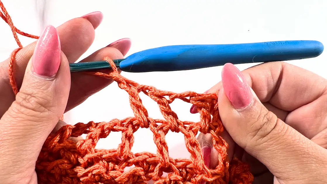 Attaching the completed bottom mesh section directly to the twisted top with stitch markers in place.