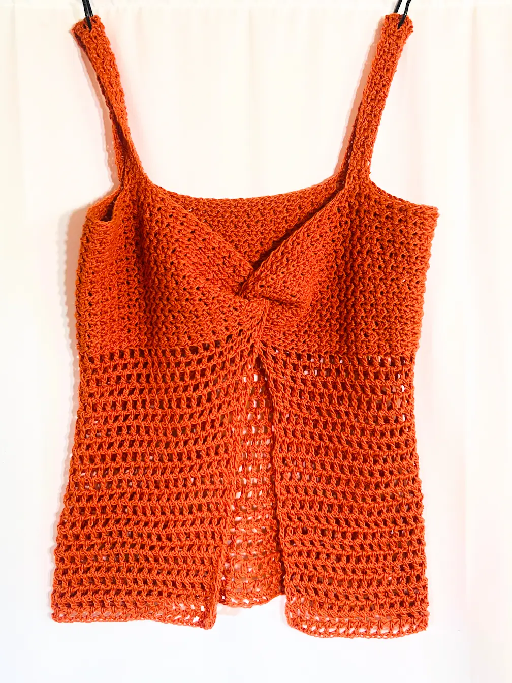 Front view of the Summer Glow Crochet Top in burnt orange, featuring a twisted bust detail and open front design.
