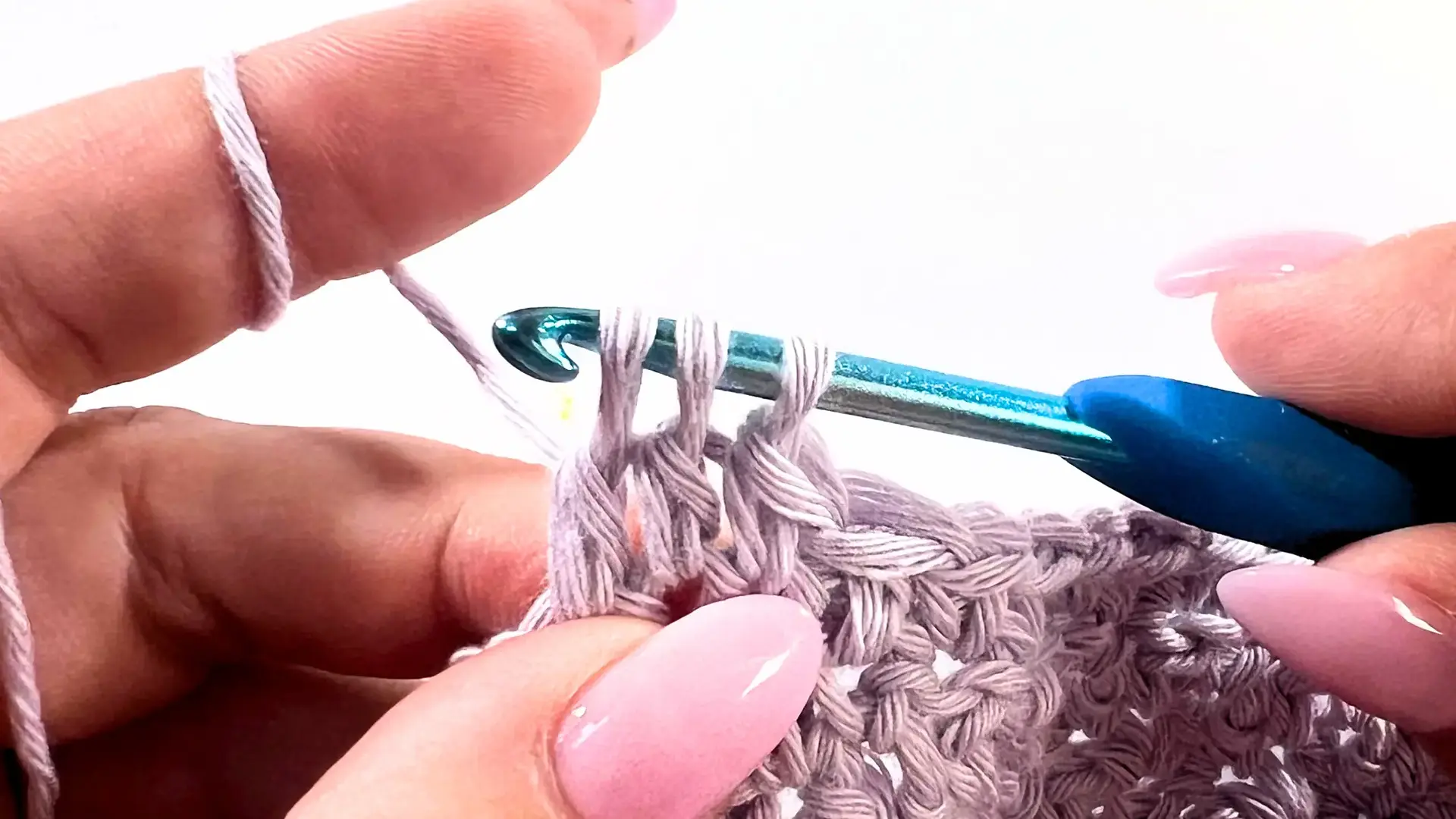 Crochet hook with yarn over pulling through the first two loops of DC2tog decrease in Lemon Peel Stitch C2C baby washcloth.
