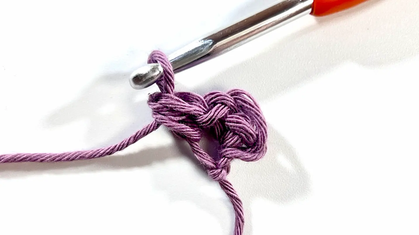 Close-up of the first completed block in C2C Even Moss Stitch using light purple yarn and a crochet hook. The texture begins to form with alternating slip stitches and half double crochets, characteristic of the Even Moss Stitch.