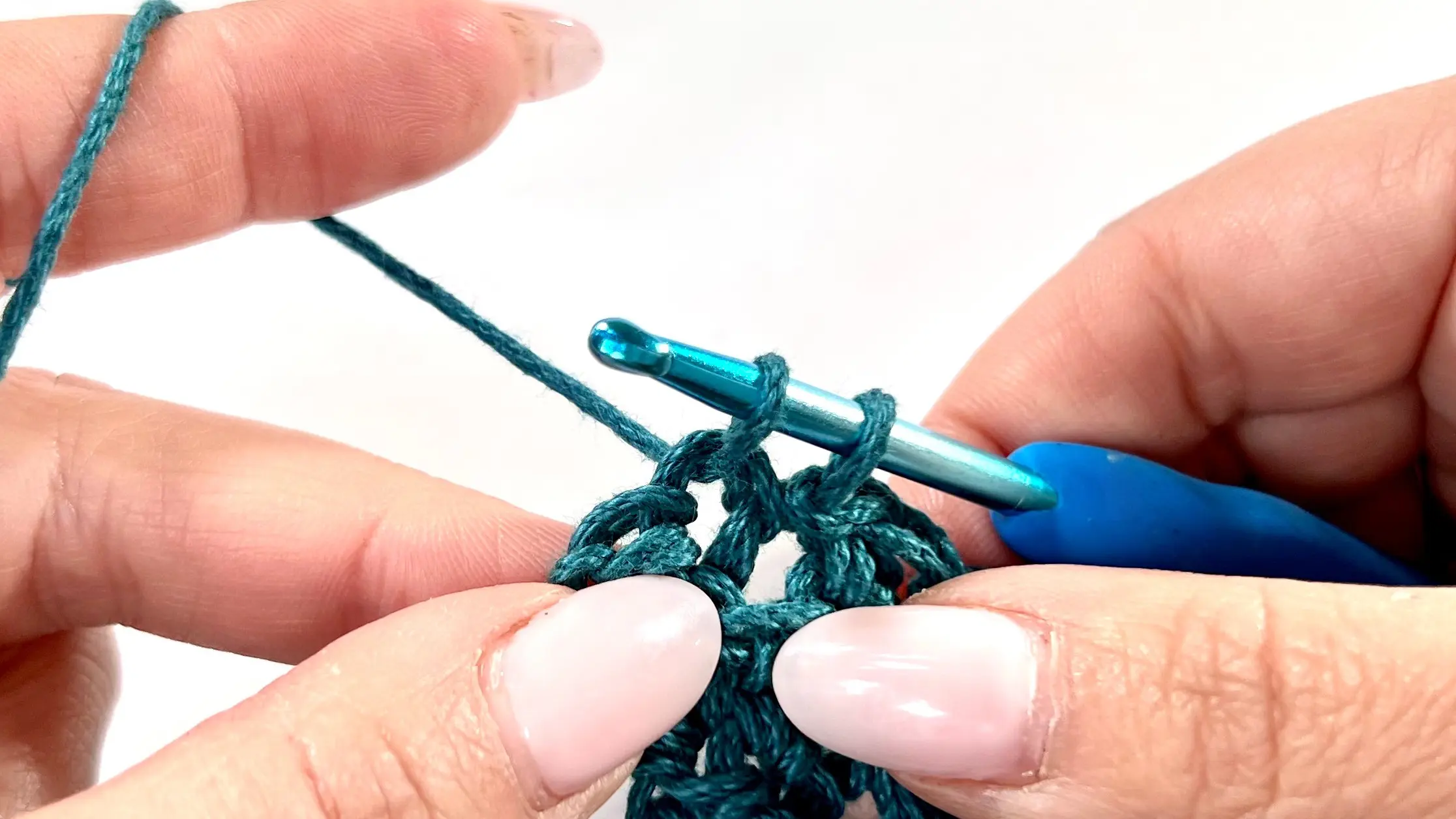 Working the decrease on the short side of the rectangle; the hook is placed in the third-to-last stitch with two stitches left unworked to shape the straight edge.