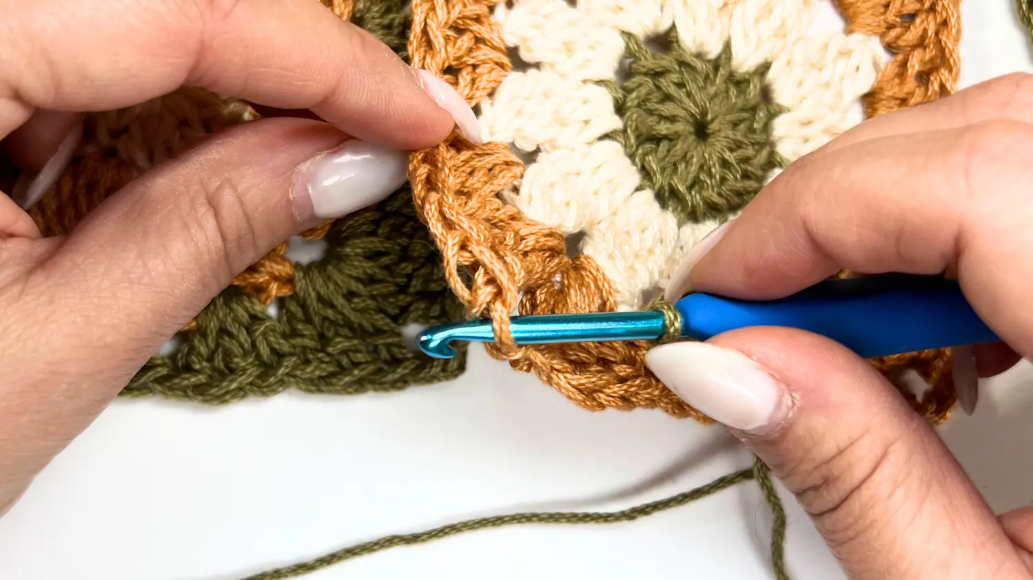 Inserting hook through the corner of two granny squares to begin the slip stitch join technique.