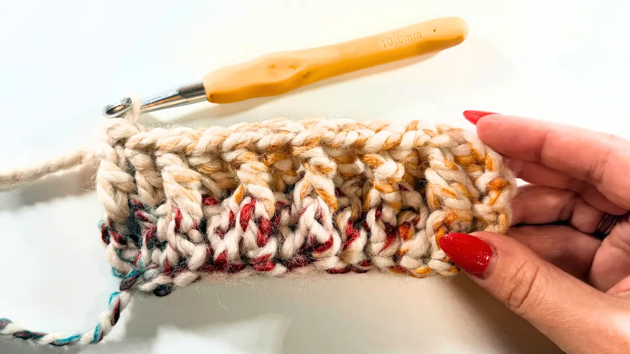 Progress of chunky crochet beanie body worked flat before seaming, showing bold vertical texture.