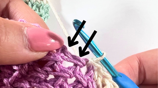 Close-up showing two arrows pointing to the next edge stitches on the side of the panel, where slip stitches will be made to continue attaching the sleeve.