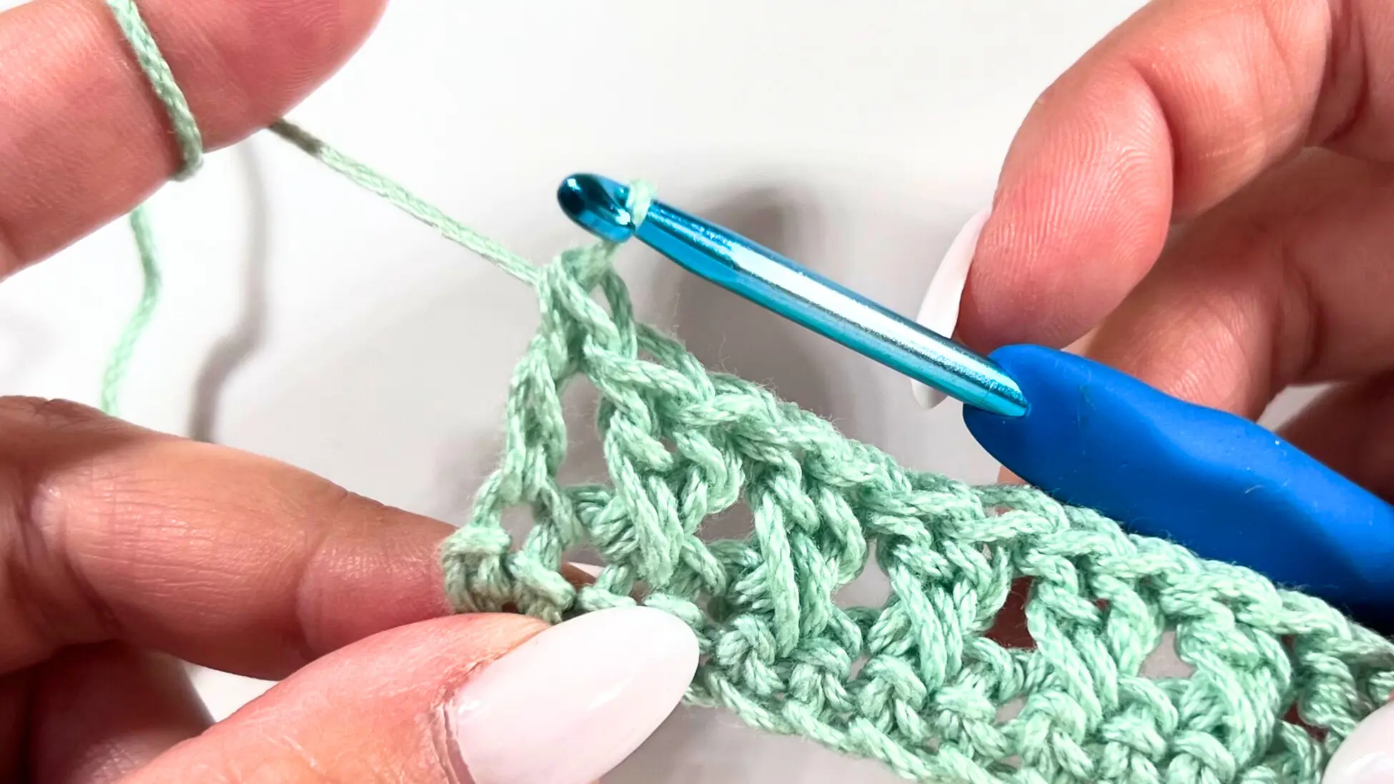 Halfway through a row of Crossed Double Crochet stitches, clearly showing the textured crossed X pattern in progress.