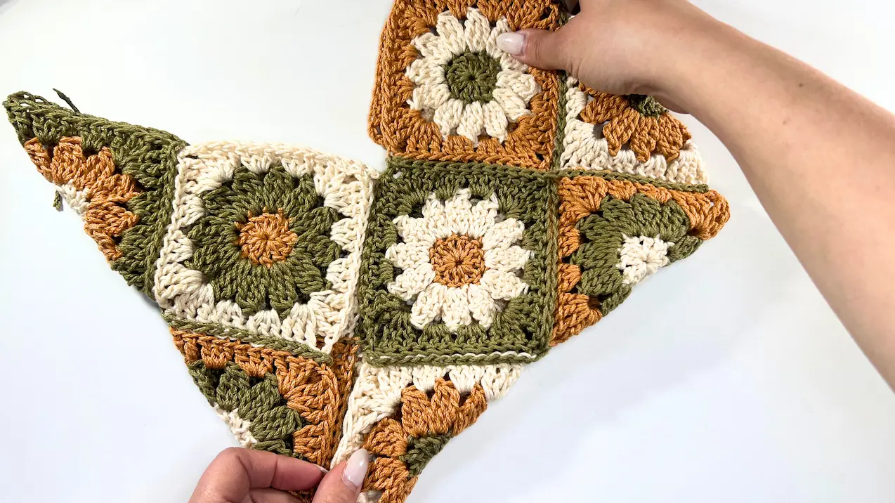 Fully folded crochet daisy square section forming the base of the bag, ready for final seaming or shaping.