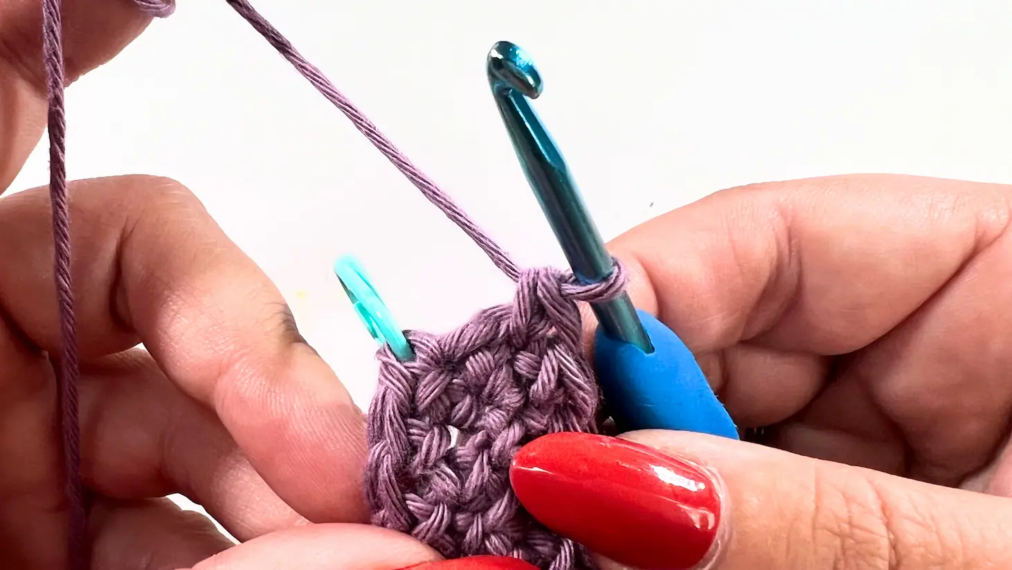 Crochet stitches with purple yarn and hook showing start of invisible join.