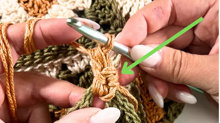 A close-up view of a single crochet, marked with an arrow to show the stitch location.