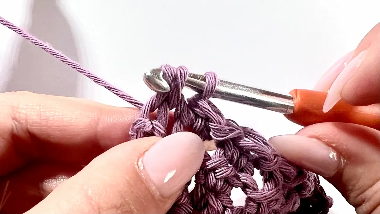 Close-up of the final stitch of a C2C Even Moss row being worked. The yarn is pulled through the remaining loops on the hook as the decrease section nears completion.