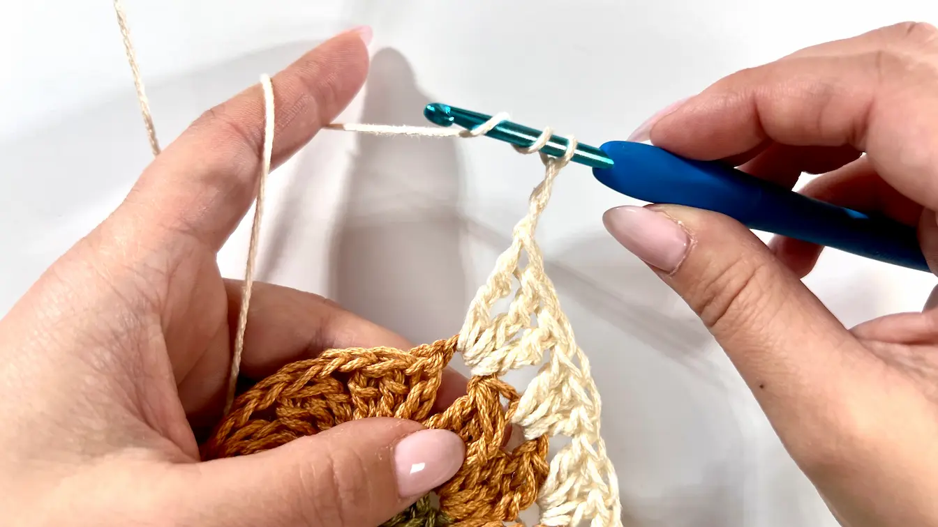 Working the first square corner using treble crochets and chain spaces on the Daisy motif.
