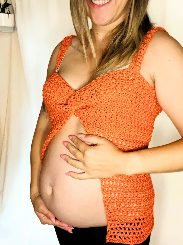 Pregnant woman wearing the Summer Glow Crochet Top, showing the twisted bust design and open belly style.