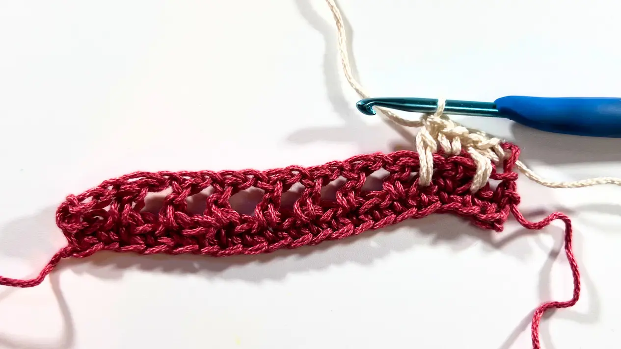 Crochet swatch in progress showing alternating SC and spike stitches across Row 3.