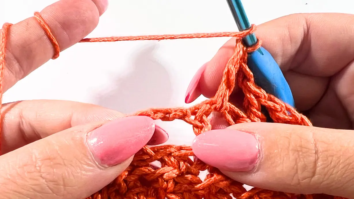 Close-up of attaching the bottom section to the twisted crochet top, with stitch markers securing the join.