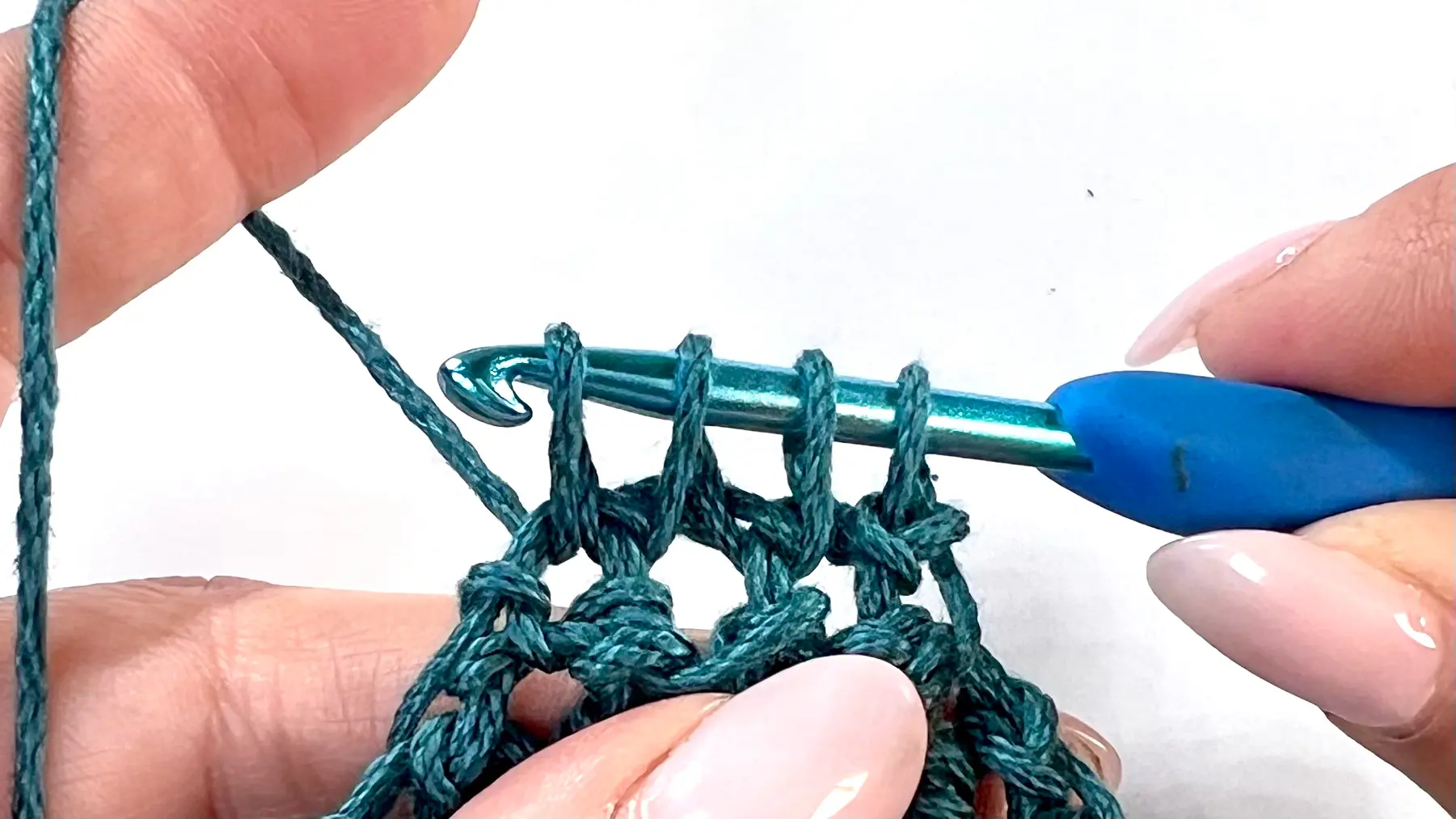 Final two stitches being worked to complete the C2C Even Moss Stitch square; the triangle tip is nearly closed with the last decrease row.