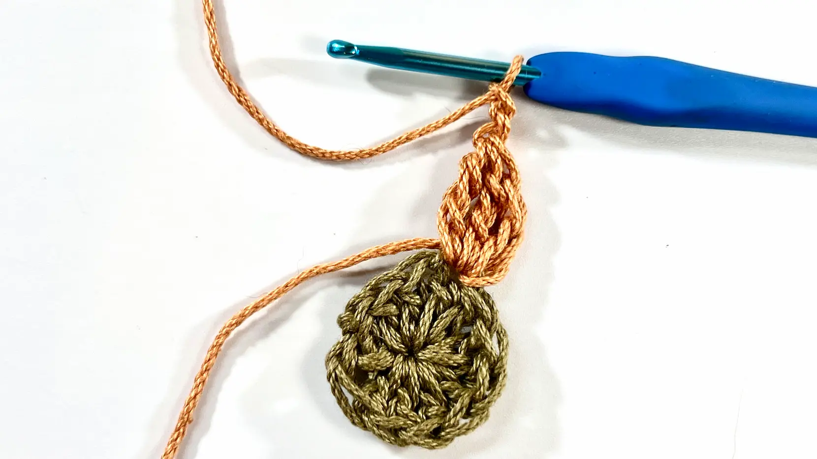 Working on the second petal of the Daisy Square with four loops on the hook, shown mid-stitch in a close-up view.