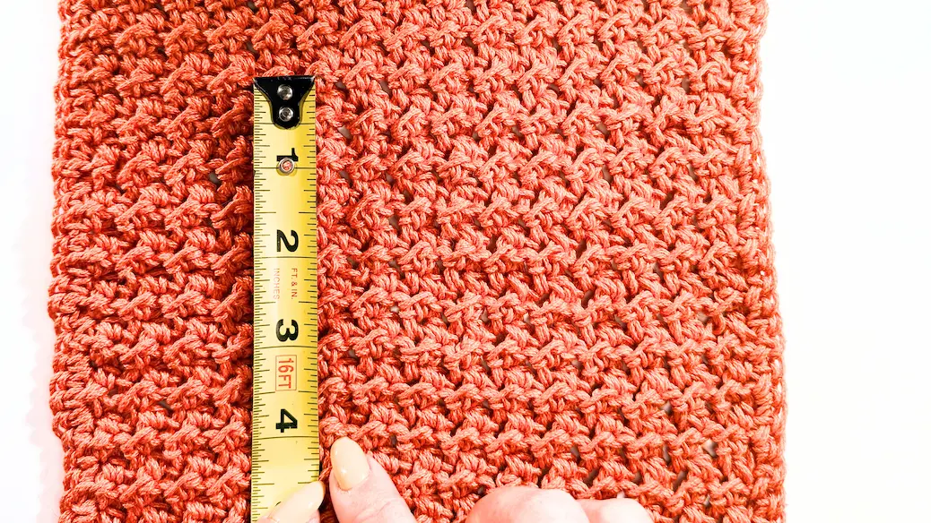 Crochet gauge swatch with tape measure showing stitch rows in a 4-inch section