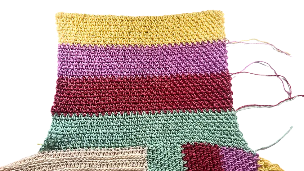 Colourful left sleeve crocheted in moss stitch, attached to the body of the sweater, featuring horizontal colour blocks in green, red, purple, and yellow with visible yarn tails for seaming.
