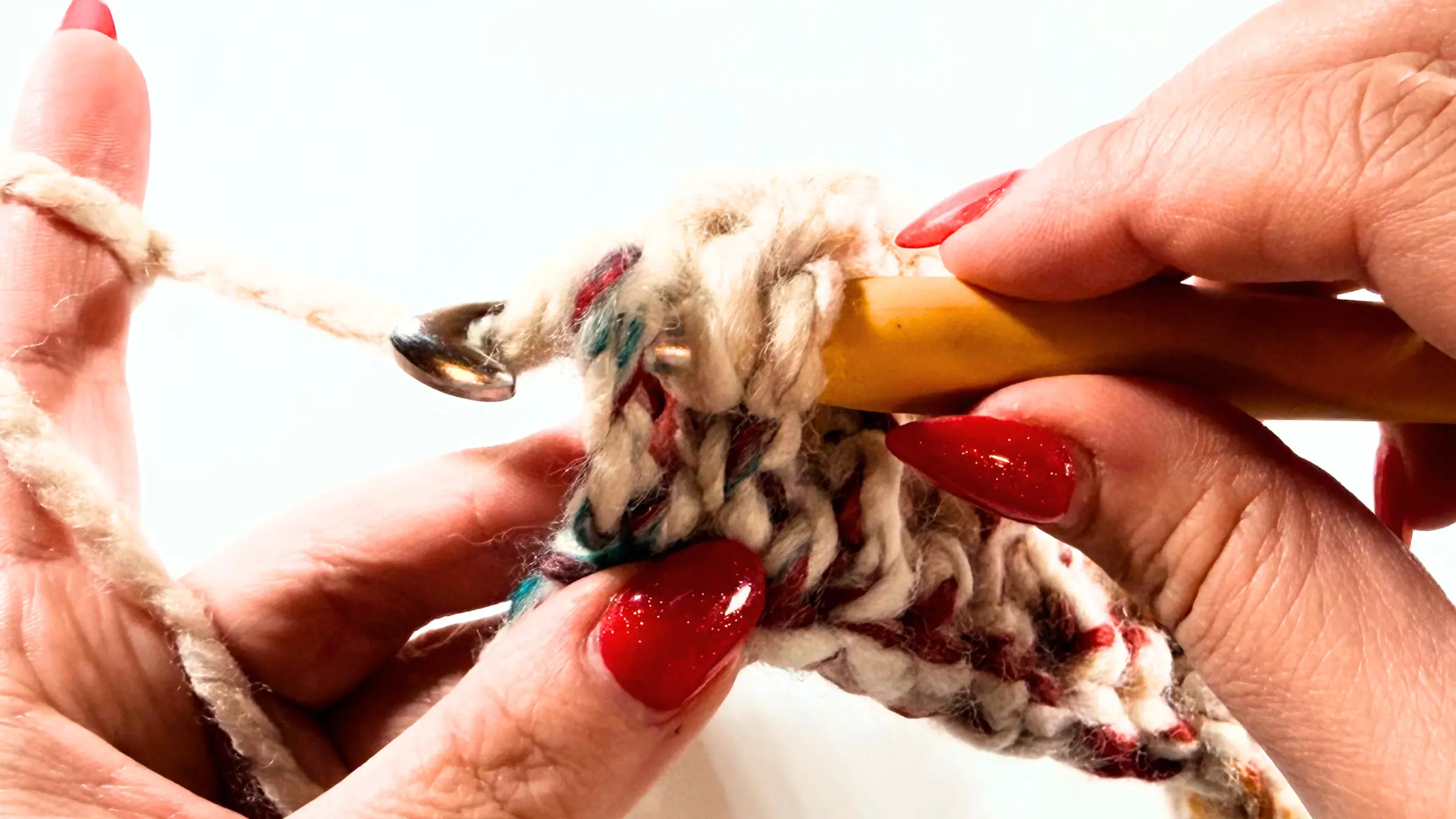 Detailed view of crochet hook working through thick loops of super bulky yarn while building textured beanie fabric.