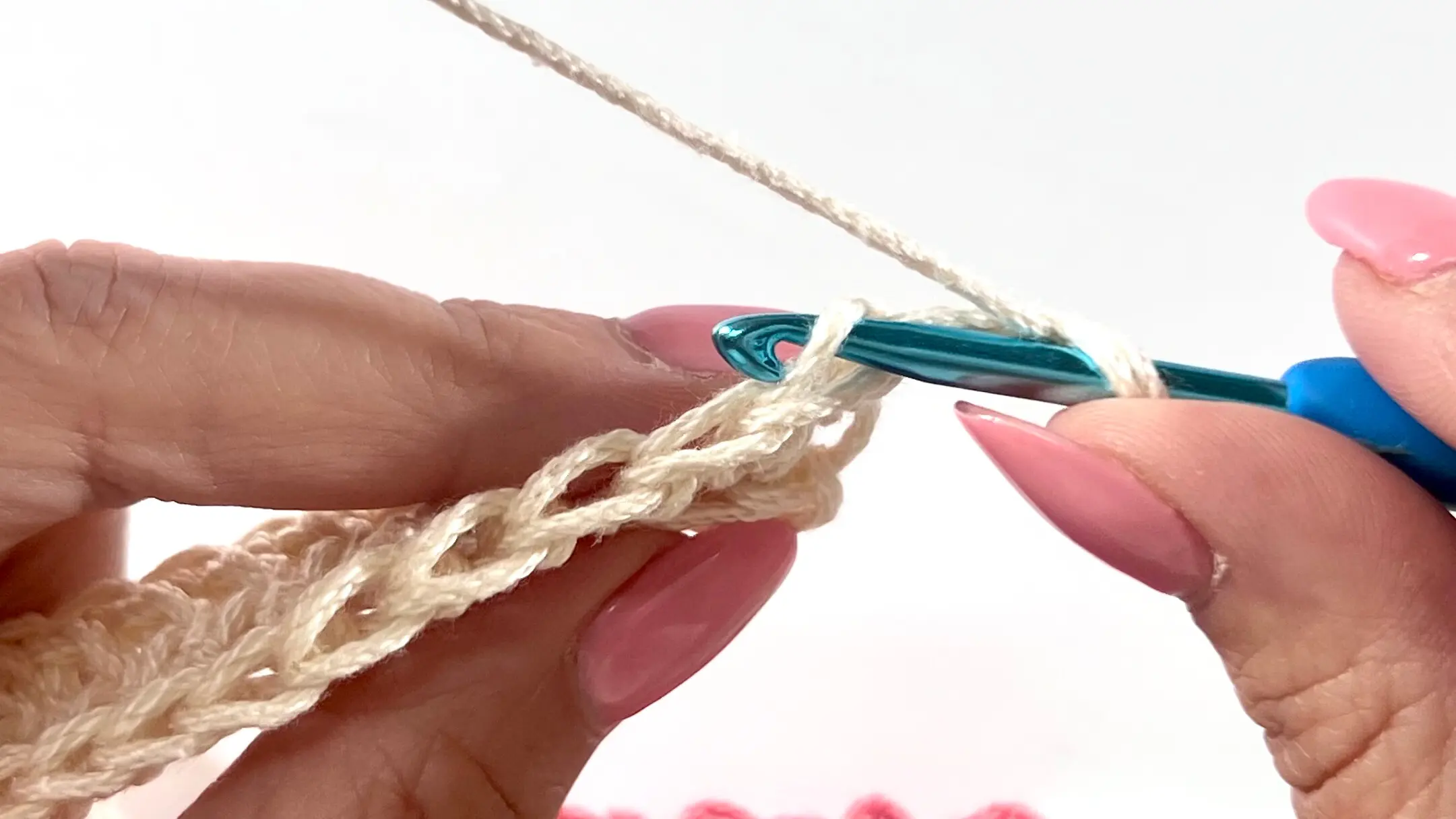Close-up of a crochet hook inserted into the back loop of the stitch, ready to work a Half Double Crochet stitch into that loop for a ribbed texture effect.