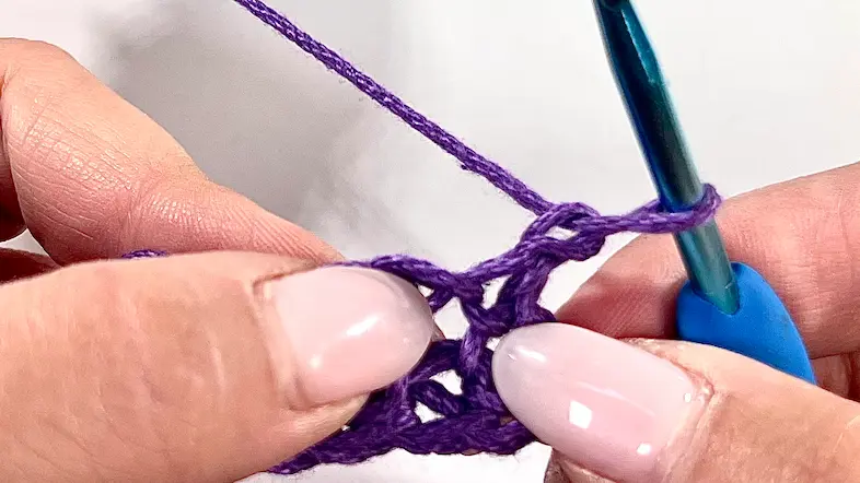 Close-up of turning the work to begin the second row of Bean Stitch; the crochet hook is ready to insert into first stitch.